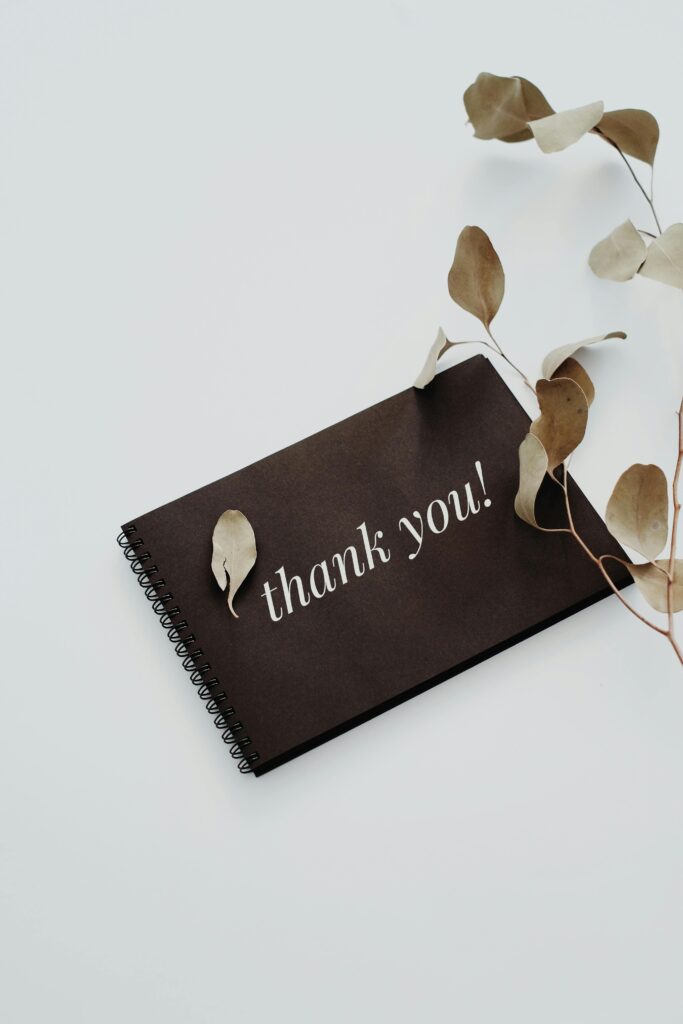 Elegant thank you note with dried eucalyptus leaves on a white background.